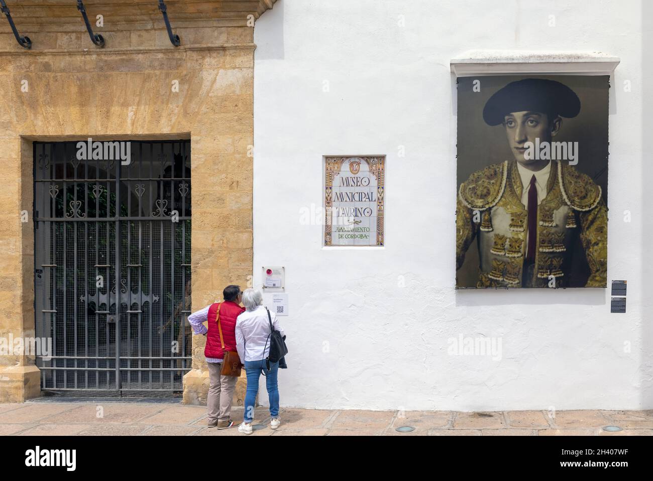 Paar vor Cordobas Museo Municipal Taurino oder dem Municipal Bullfight Museum. Das Foto an der Wand zeigt den berühmten Stierkämpfer Manuel Laureano R Stockfoto