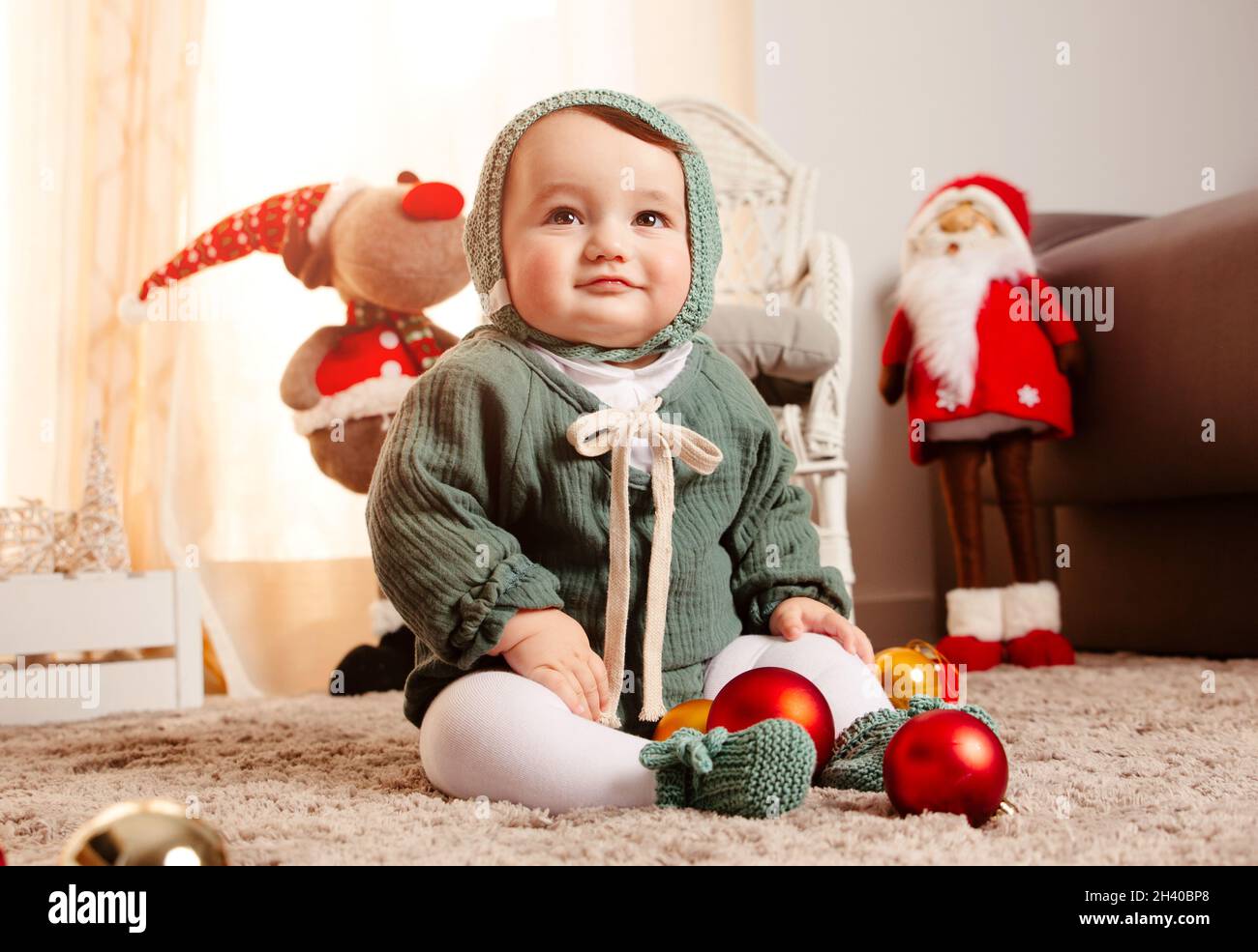 Niedliches Baby mit weihnachtskleidung und Ornamenten. Glückliches Kind  sitzt in der Nähe von weihnachtsbällen und lächelt. Frohe Weihnachten und  Winter-Weihnachtszeit-Konzept Stockfotografie - Alamy