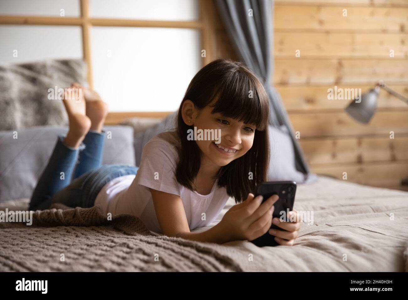 Happy Smiling Gen Z Mädchen mit Smartphone im Schlafzimmer Stockfoto