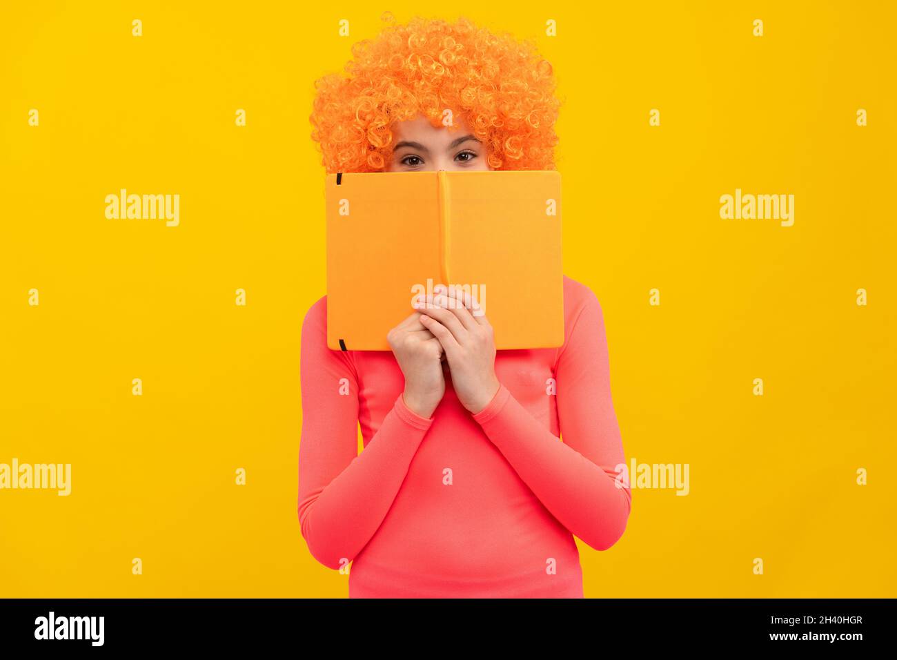Bookworm in der Schulung. Funky Bücherwurm gelben Hintergrund. Happy Kid Cover Gesicht mit Buch Stockfoto