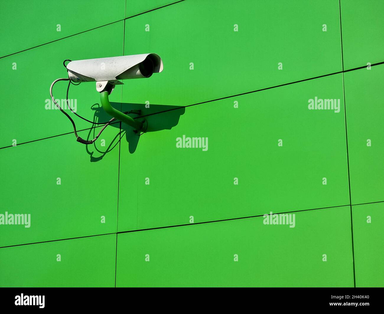 Eine einzige CCTV-Live-Videoüberwachungskamera an einer grünen Wand, Nahaufnahme, Kopierbereich. Städtische Sicherheits- und Sicherheitseinrichtungen, Stadtüberwachung, Mangel an pri Stockfoto