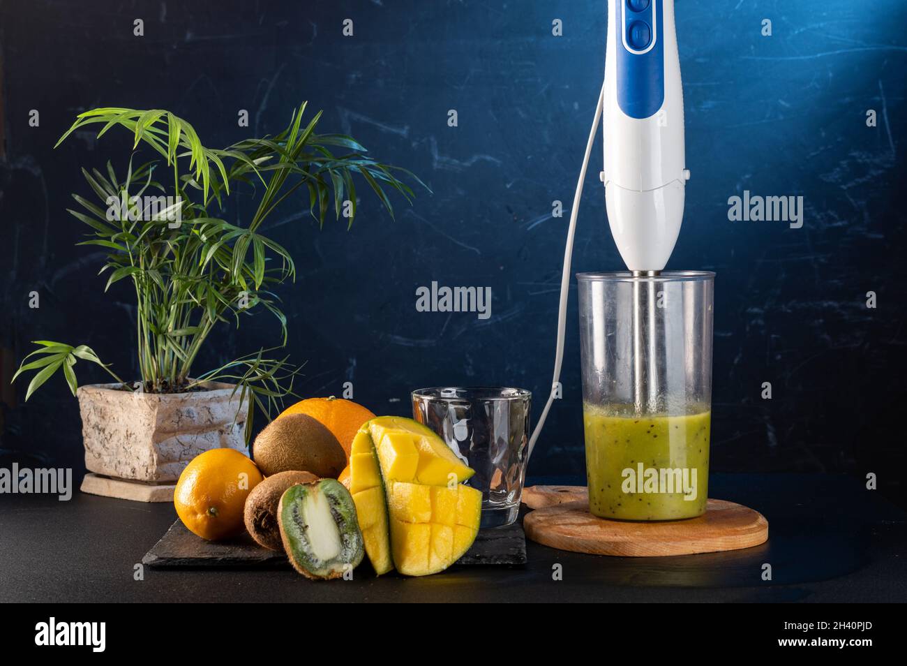 Obst und Mixer. Smoothies in einem Mixer zubereiten. Schneiden Sie die Früchte in einem Mixer. Frisch zubereitete Smoothies und Mixer. Vorderansicht. Stockfoto