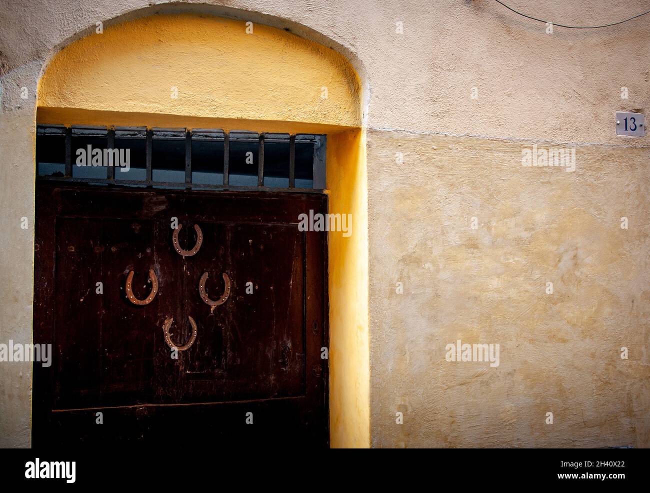 Vier umgedrehte Hufeisen an einer großen Eingangstür in Italien, die gerade die Nummer dreizehn war. Glück oder Pech. Stockfoto