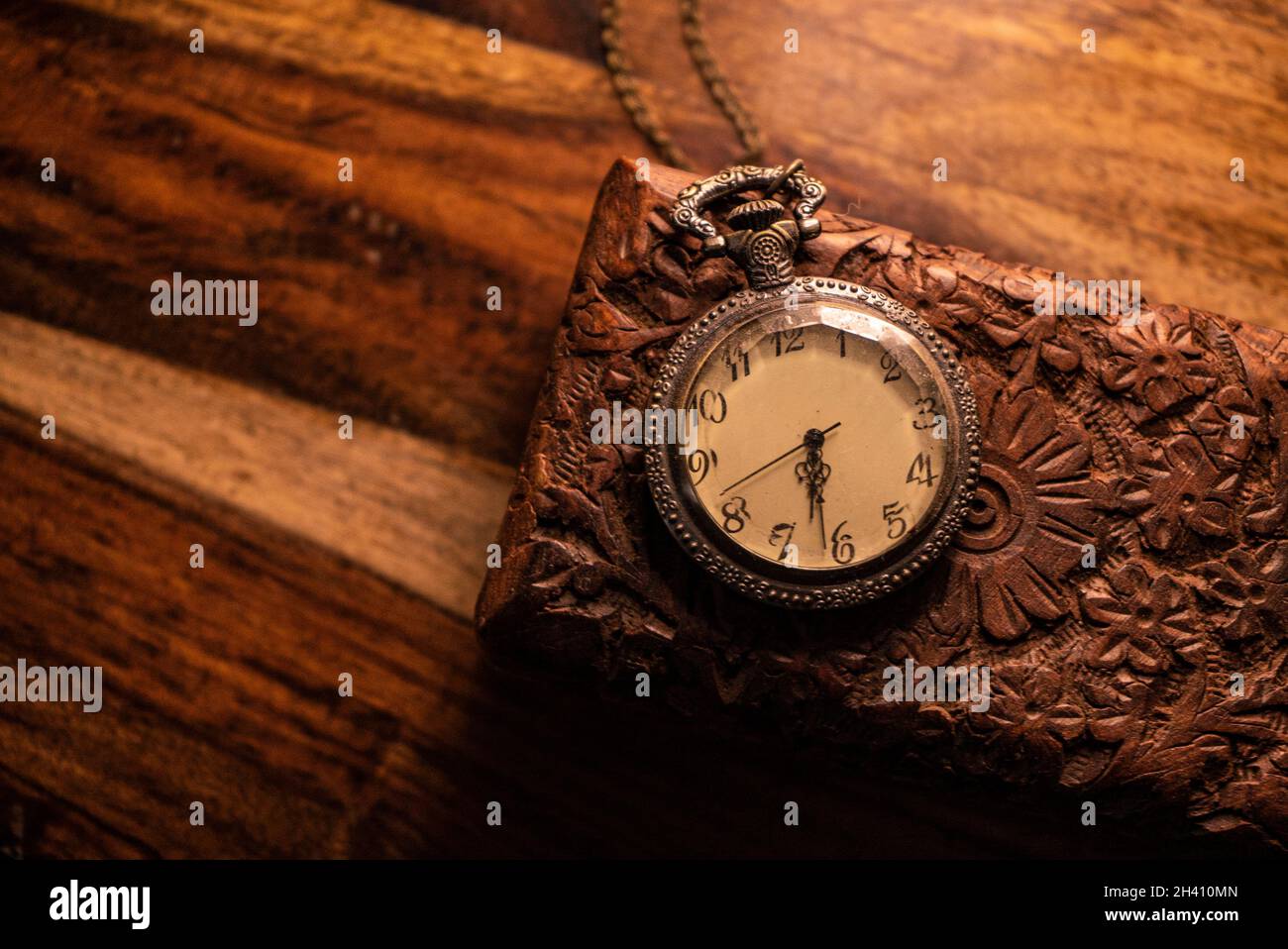 Auf dem Tisch steht eine alte Taschenuhr über einem alten Holzkoffer. Vintage Hintergrund aus einer Sammlung von Antiquitäten. Nahaufnahme und ausgewählter Fokus Stockfoto Auf dem Tisch steht eine alte Taschenuhr über einem alten Holzkoffer. Vintage Hintergrund aus einer Sammlung von Antiquitäten. Nahaufnahme und ausgewählter Fokus Stockfoto