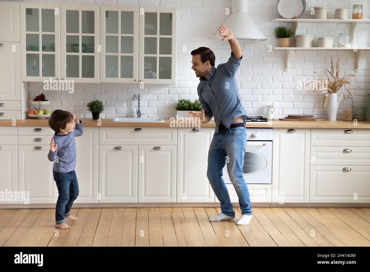 Glücklich liebenswert kleinen Jungen tanzen mit fröhlichen Vater zu Hause. Stockfoto