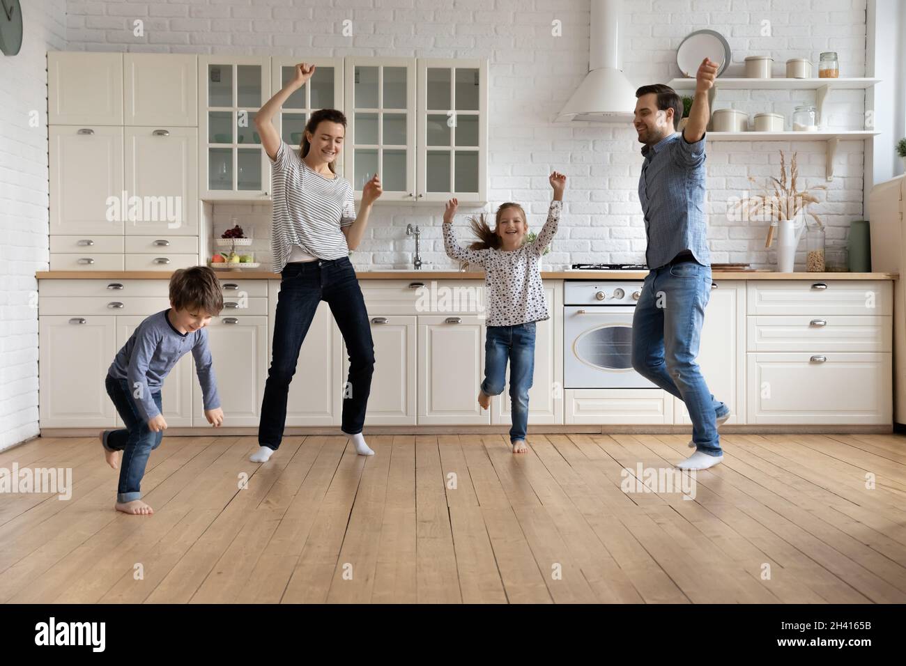 Glückliche junge Paar Eltern tanzen mit kleinen Kindern. Stockfoto