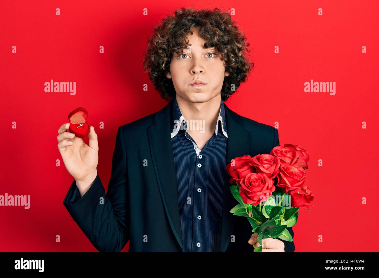 Hübscher junger Mann mit Blumenstrauß und Verlobungsring mit lustigen Wangen. Mund mit Luft aufgeblasen, Luft fangen. Stockfoto