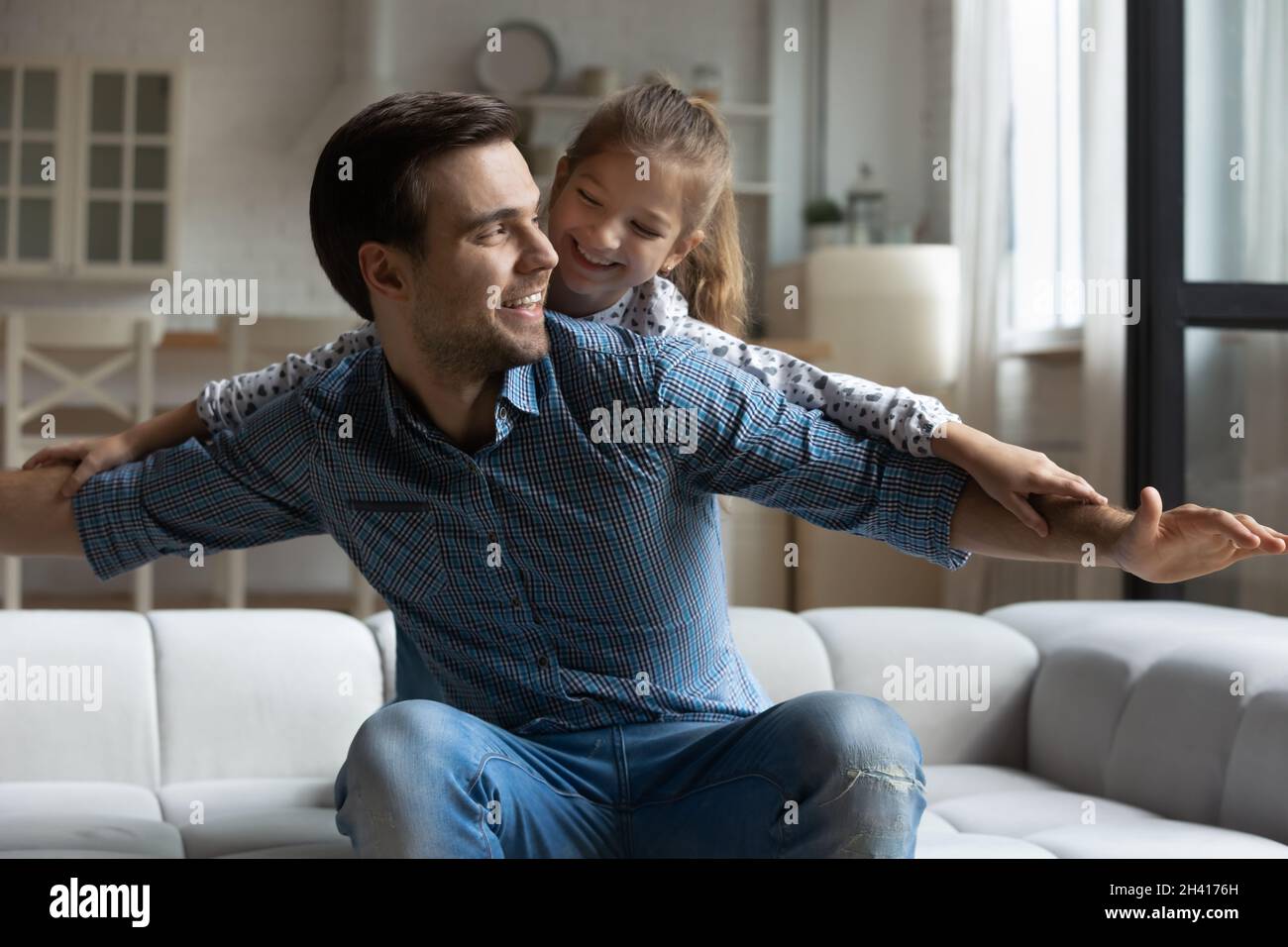 Fröhlicher junger Vater, der mit einer kleinen Tochter spielt. Stockfoto