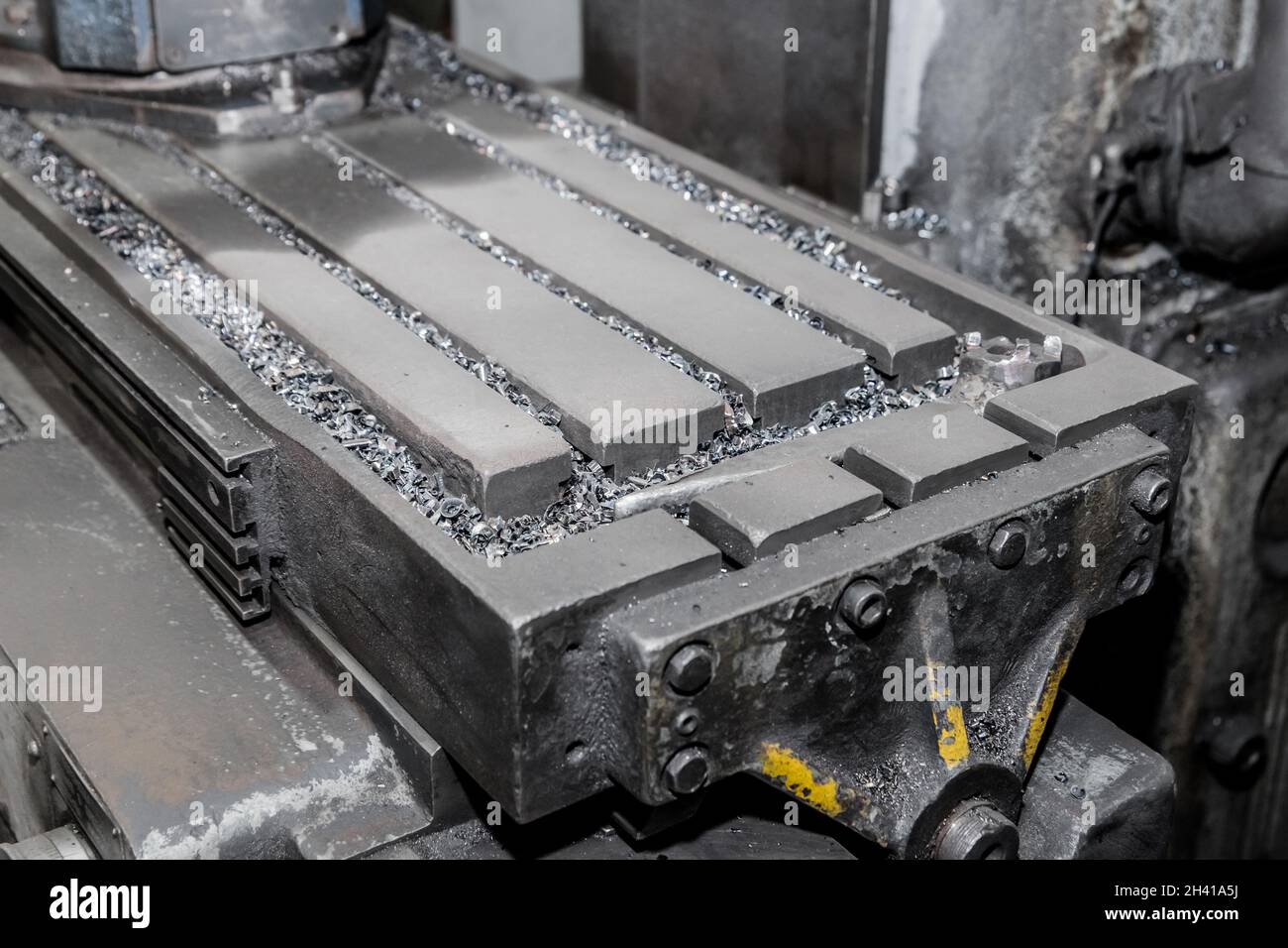 Nahaufnahme eines Teils der horizontalen Fräsmaschinen und Werkzeuge mit Eisenabfällen nach der Metallbearbeitung in der Werkstatt der Industrieanlage. Stockfoto