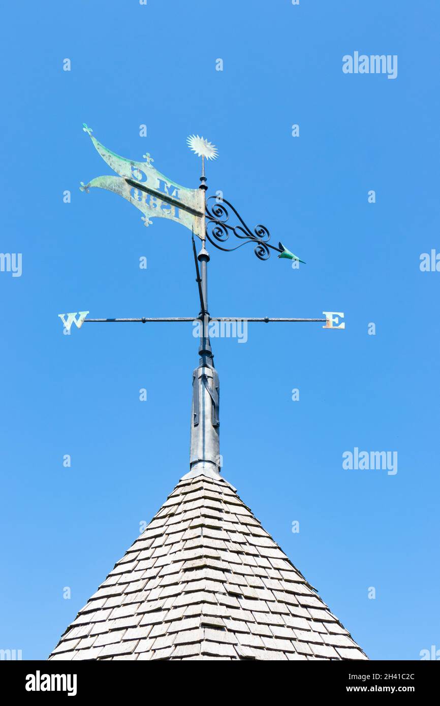 Wetterfahne auf spitzem Ziegeldach gegen blauen Himmel Stockfoto