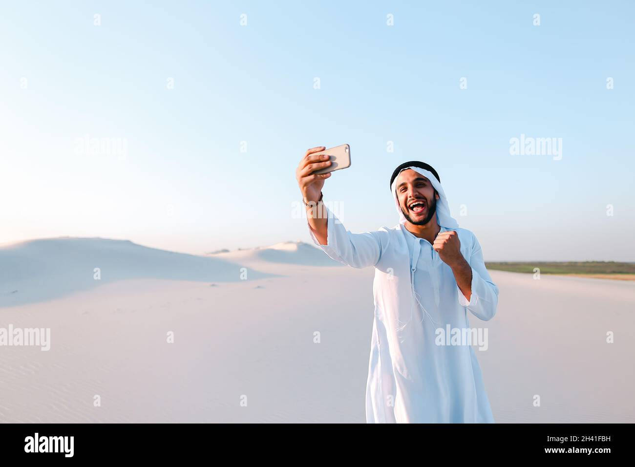 Portrait des arabischen scheich-Mannes mit Gadget, das am Sommertag in skype gegen den blauen Himmel kommuniziert. Stockfoto