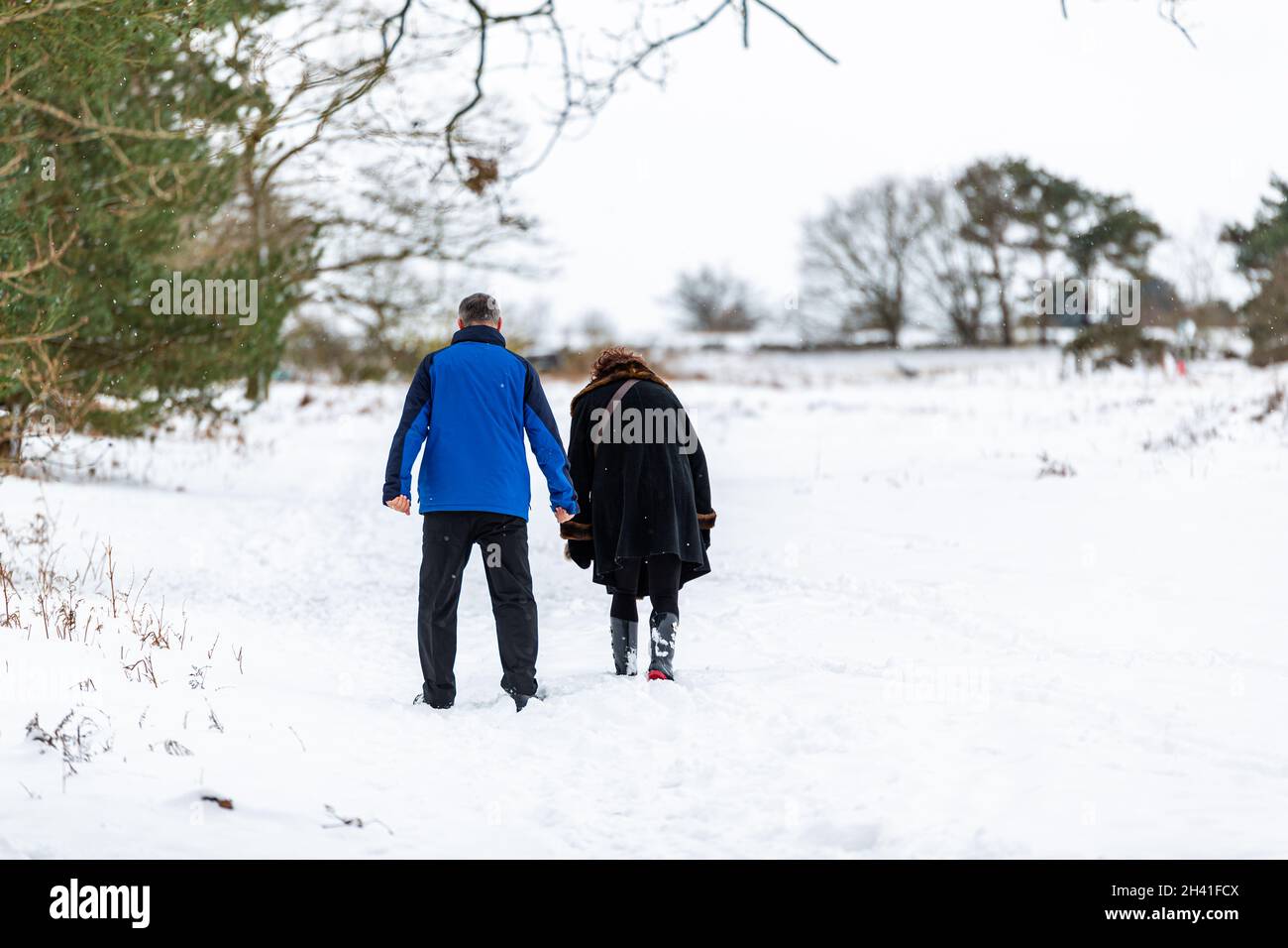 Ein unbekanntes Paar, das durch eine verschneite Landschaft spazierengeht Stockfoto