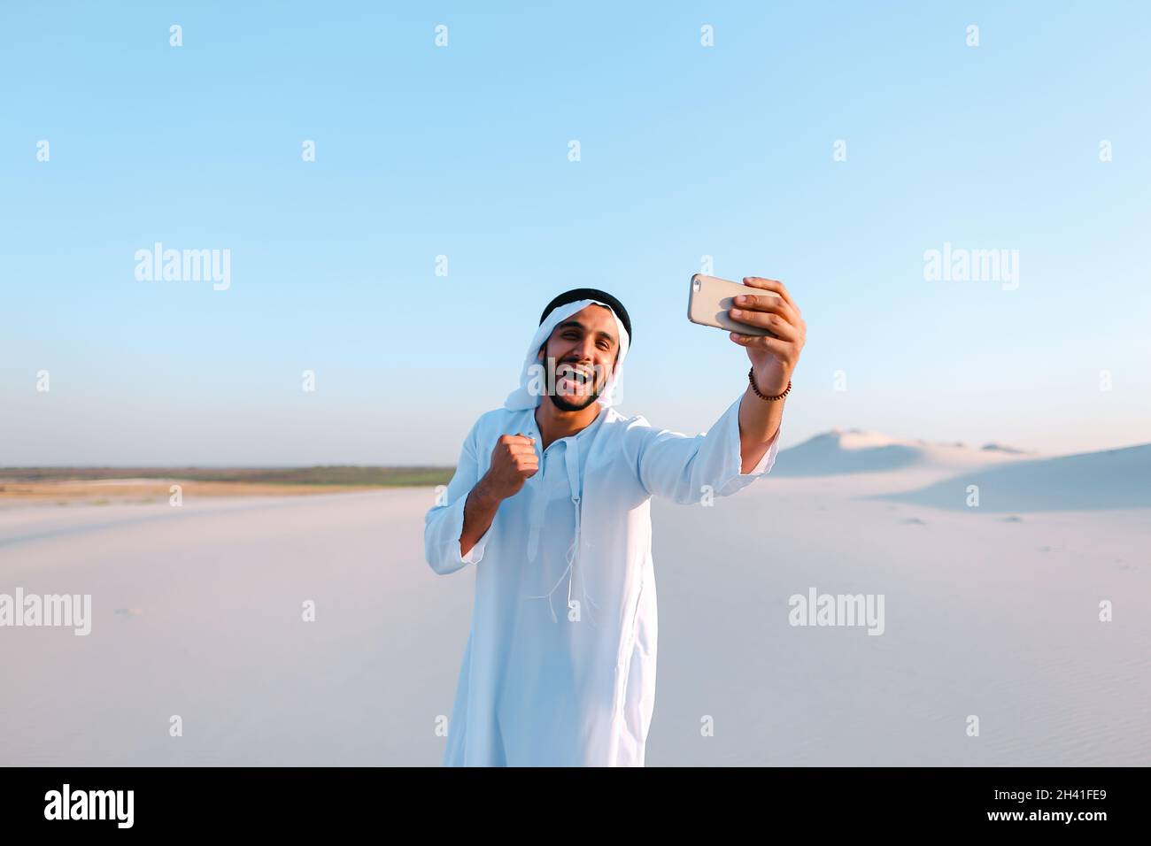 Portrait des arabischen scheich-Mannes mit Gadget, das am Sommertag in skype gegen den blauen Himmel kommuniziert. Stockfoto