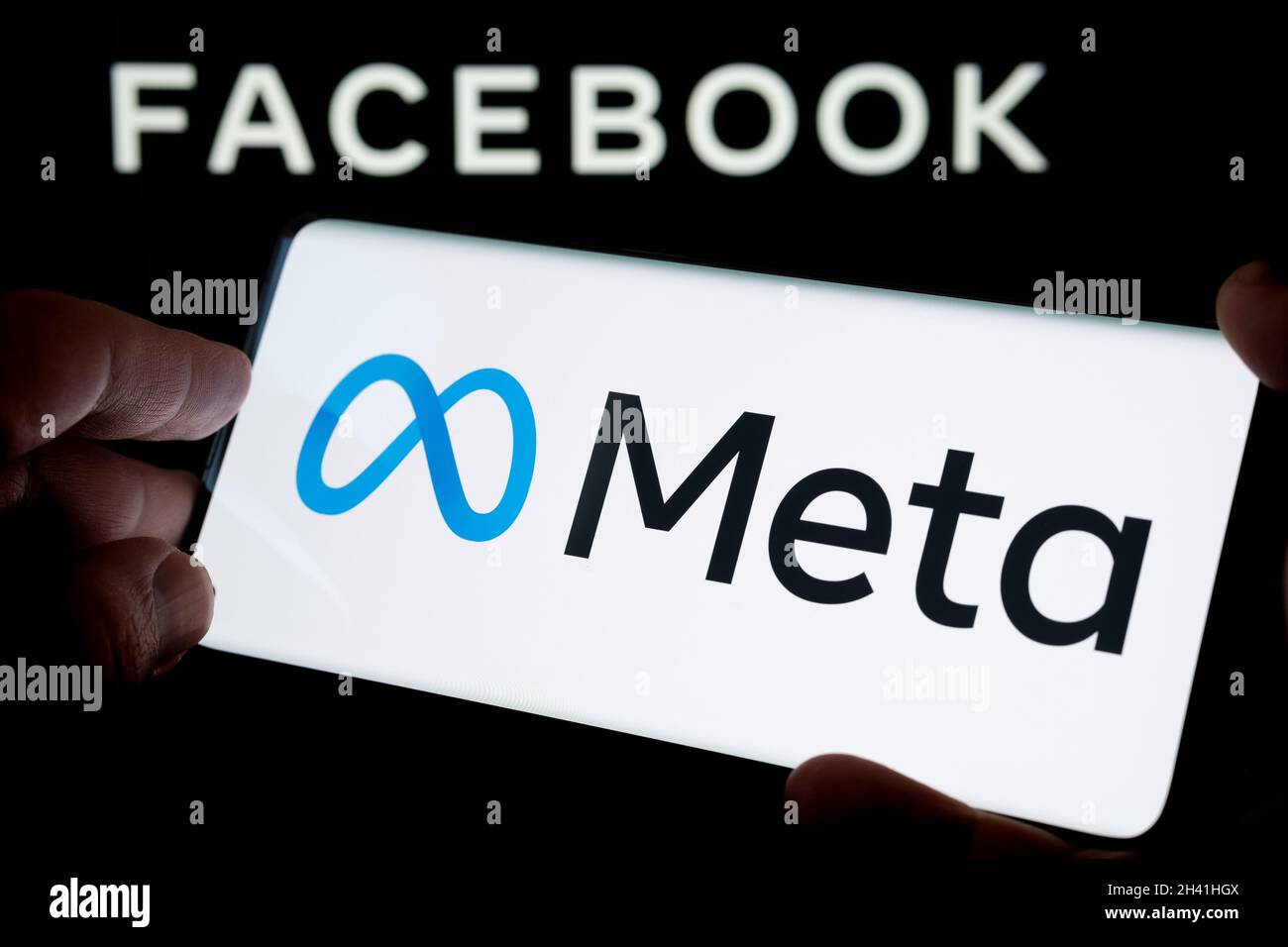 FACEBOOK META Firmenlogo gesehen Smartphone halten in der Hand mit verschwommenem Facebook inc. Logo auf Laptop-Bildschirm hinter. Selektiver Fokus. Stafford, Vereinigte Ki Stockfoto