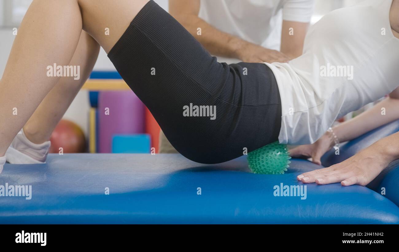 Frau tut Selbstmassage mit Spiky Massage Ball bewegen den Körper auf und ab. Stockfoto