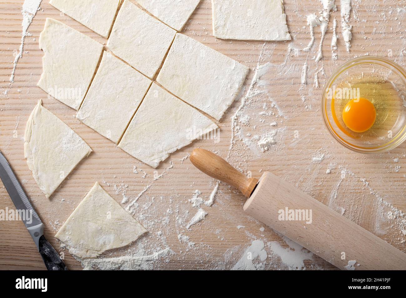 Backzutaten wie frisches Ei, Mehl und ein Nudelholz auf einem Holztisch - Draufsicht Stockfoto