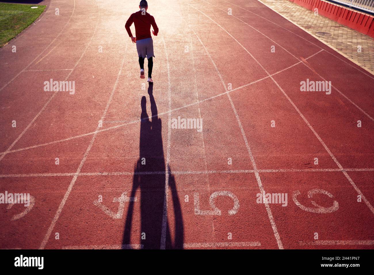 Ein junger Mann läuft an einem schönen Tag im Stadion bei einem sportlichen Training. Sport, Leichtathletik, Sportler Stockfoto