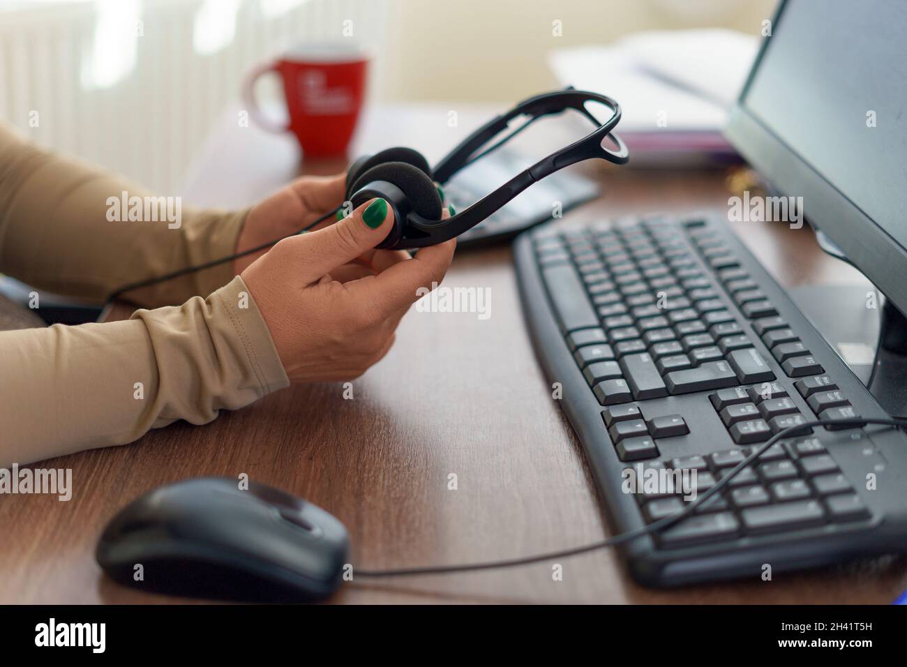 Kaukasische Frau Hände halten Mikrofon-Headset. Call Center, Büro, Remote oder Work from Home Konzept. Stockfoto