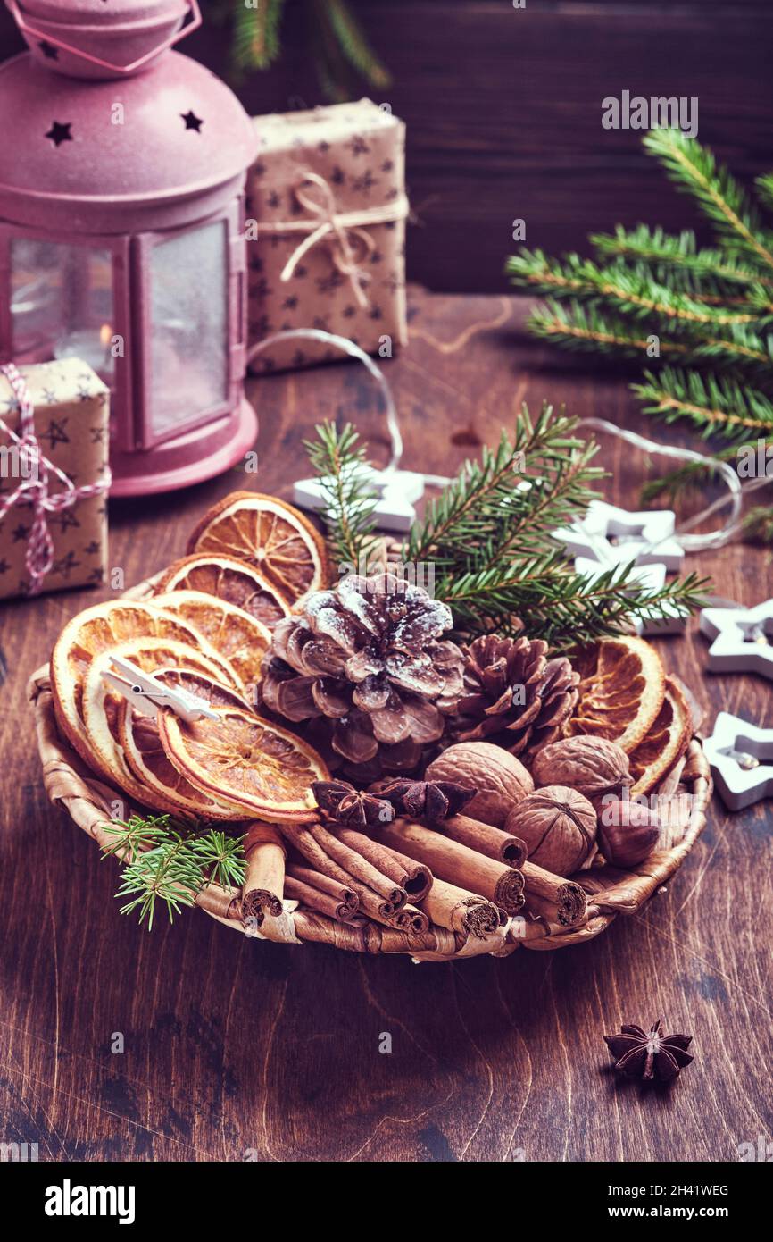 Getrocknete Orange, Sternanise, Zimt, Tannenzapfen und Tannenbaum in rustikalem Teller auf Holztisch. Hausgemachte Medley-Idee für Weihnachtsstimmung und Aroma. Öko-Frie Stockfoto