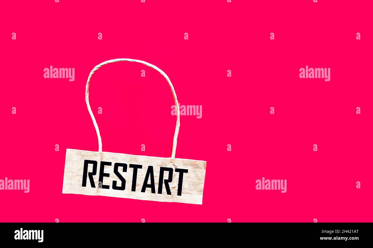 Das Wort Restart steht auf dem braunen Preisschild und dem roten Hintergrund. Geschäftskonzept. Speicherplatz kopieren. Stockfoto