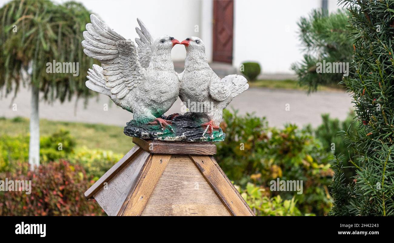 Holzfigur von zwei schönen weißen Tauben, die sich im Garten küssen Stockfoto