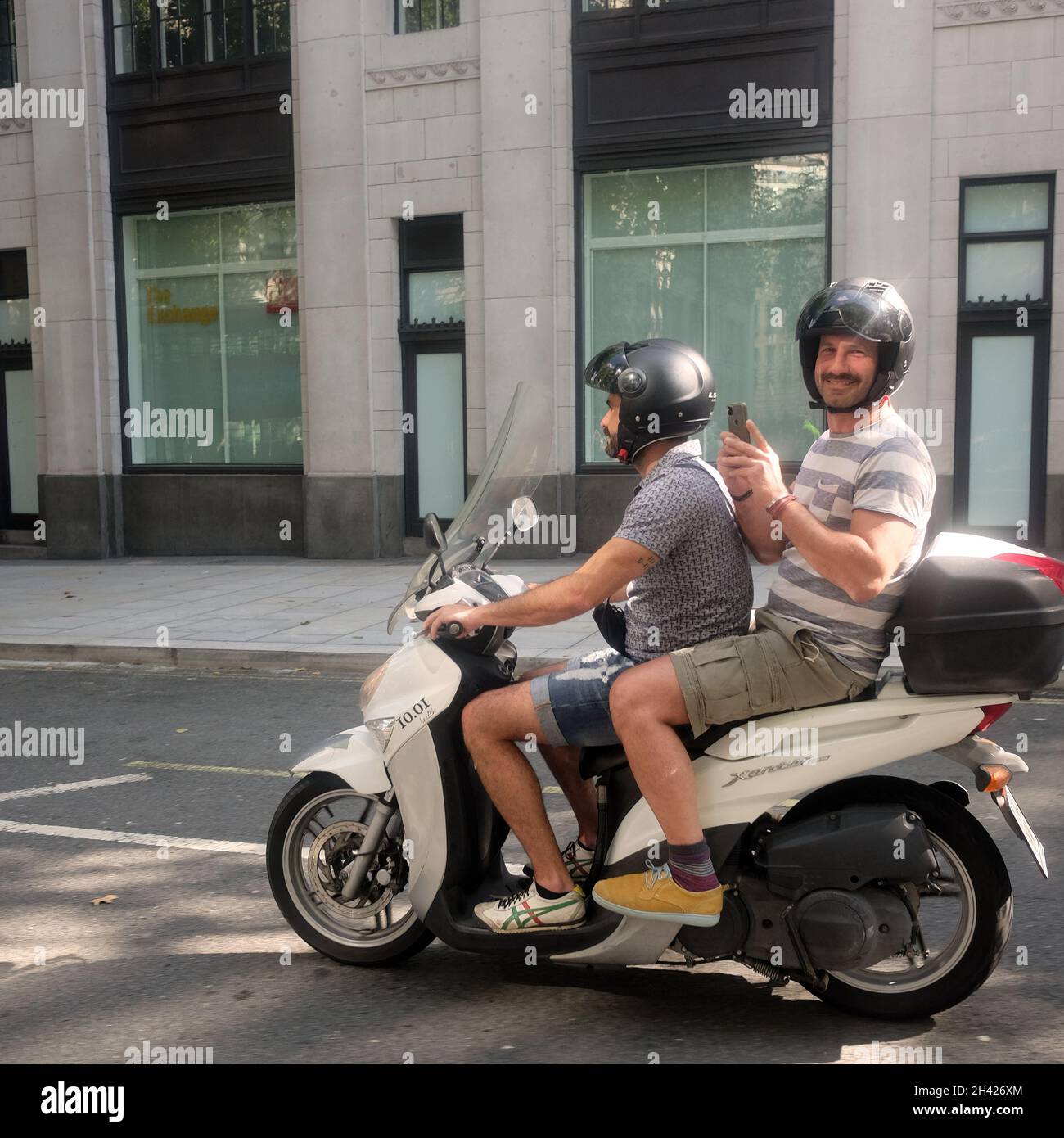 2021. August - zwei Jungs auf einem kleinen spanischen registrierten Schritt durch Motorrad oder Roller im Zentrum von London. Stockfoto