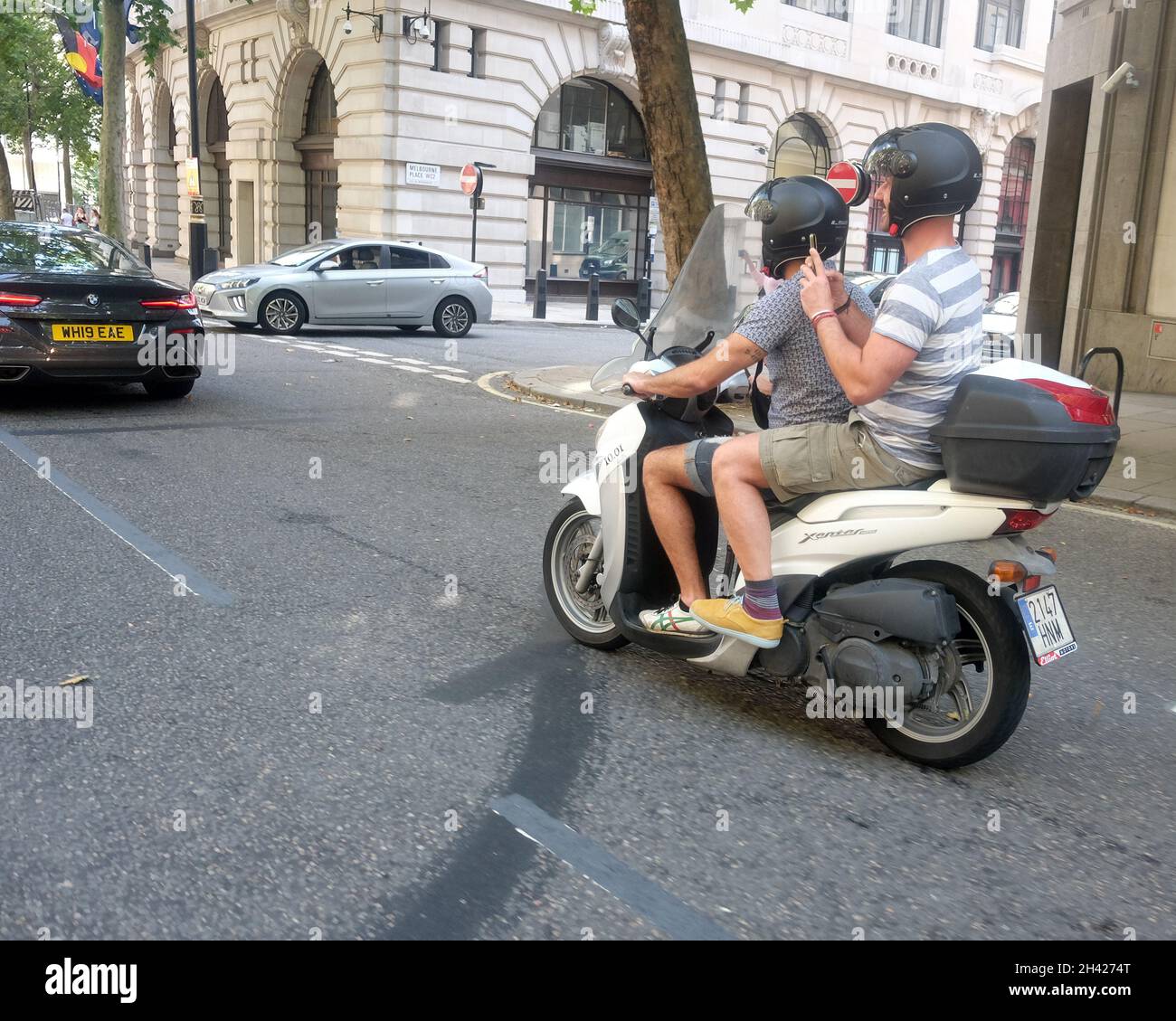 2021. August - zwei Jungs auf einem kleinen spanischen registrierten Schritt durch Motorrad oder Roller im Zentrum von London. Stockfoto