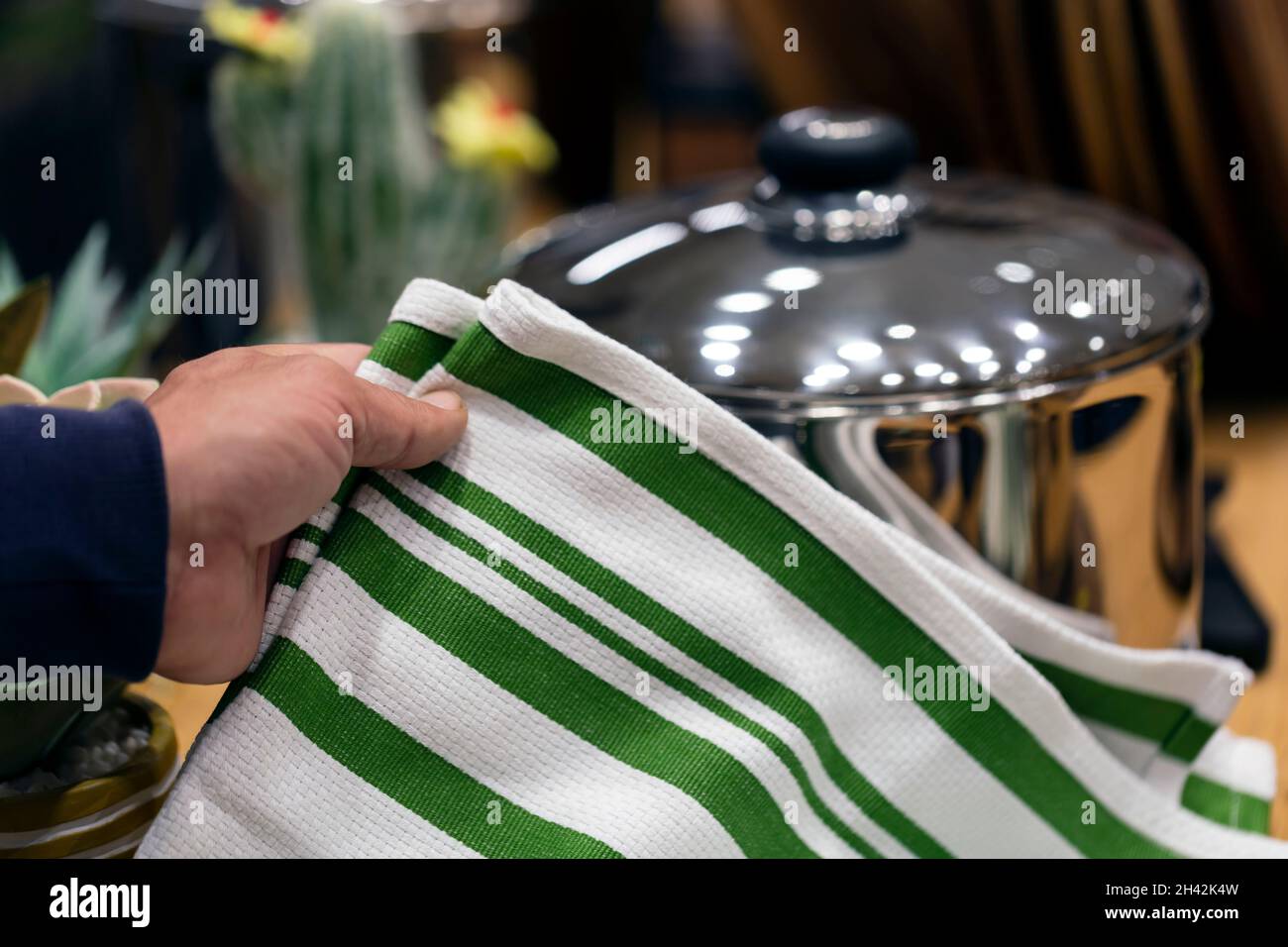 Gestreifte grobe schwere Bettwäsche Küchen- oder Handtücher. Heimtextilien, Küchengeräte, selektiver Fokus. Nahaufnahme männliche Hand mit einem sauberen weißen Handtuch. Stockfoto