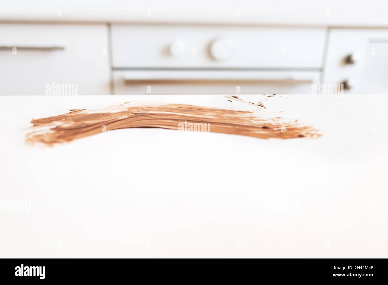 Spuren von verschmierter Schokolade auf einem weißen Tisch in der Küche Stockfoto