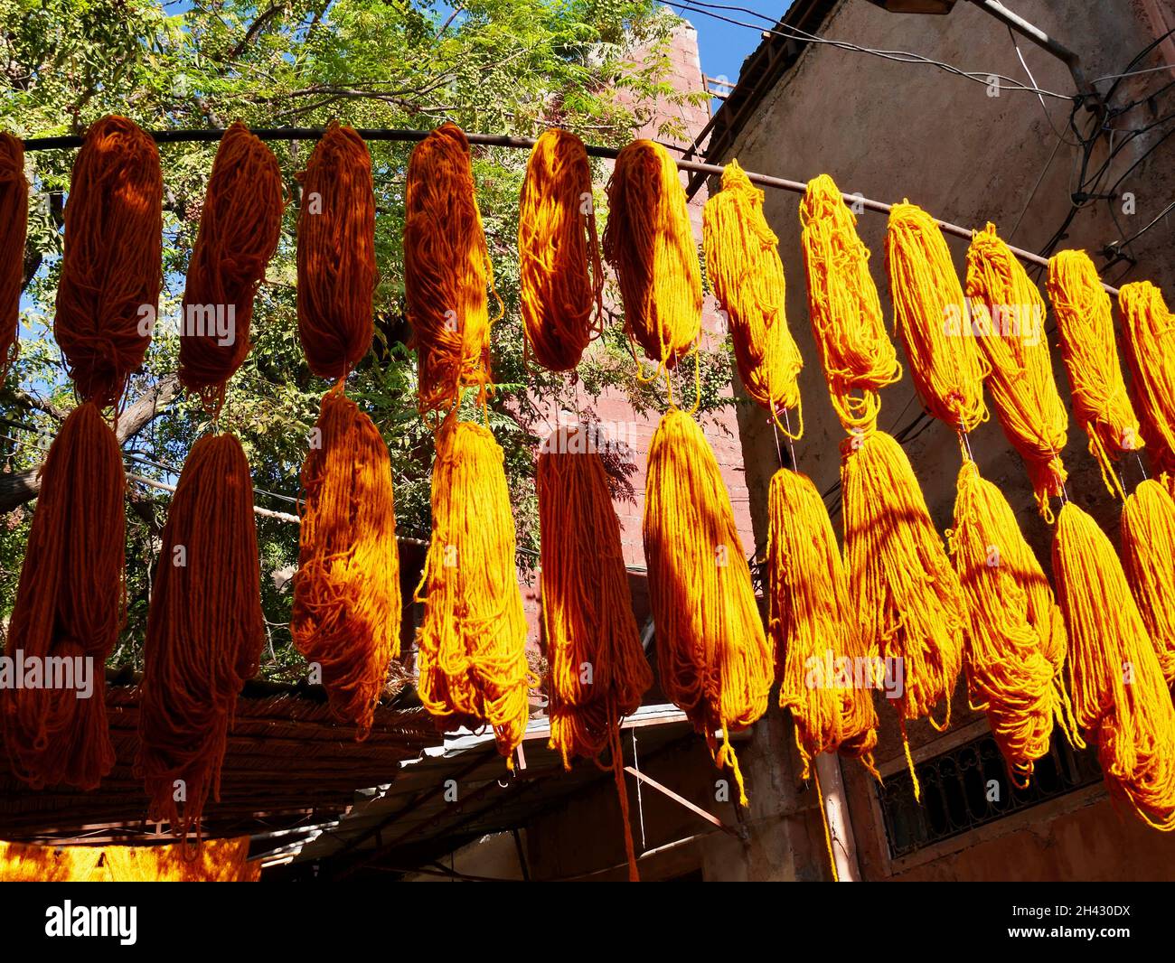 Bündeln aus orangefarbener Wolle hängen zum Trocknen an Färsen Souk, Marrakesch, Marokko. Stockfoto