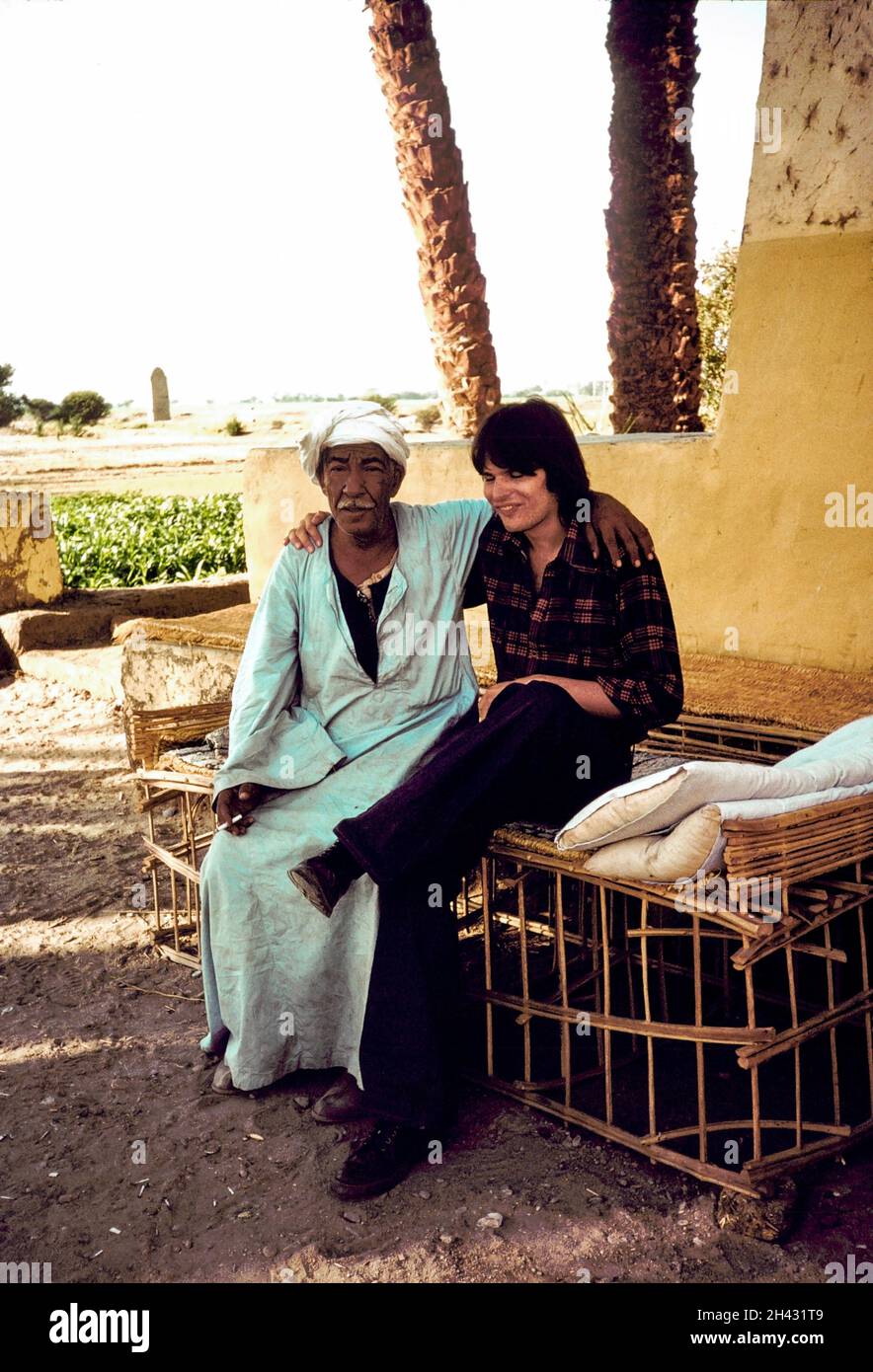 Afrika, Ägypten, Der Nil 1976. Scheich Ali Rassoul mit einem Touristen in seinem Gästehaus (Marsam Hotel) in Qurna am Westufer in der Nähe von Luxor. Sie sitzen auf Schlafbetten, die draußen an heißen Nächten zur Verfügung gestellt werden. (Foto von Maryanne Grant-Traylen). Stockfoto