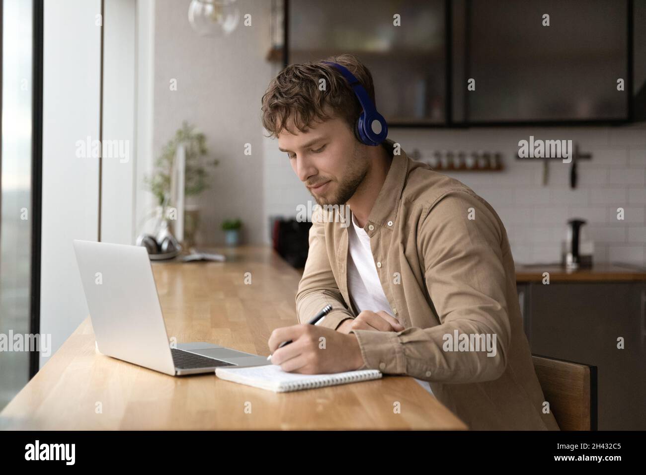 Glücklicher junger schöner Mann e-Learning, Notizen schreiben. Stockfoto
