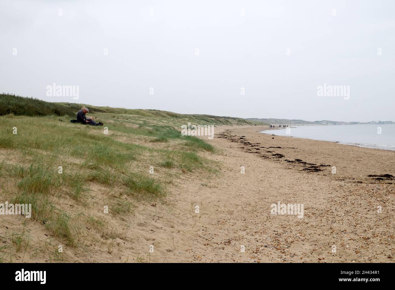 Pärchen sitzen und Menschen wandern in der Landschaft am Strand von Camber Sands im Oktober Herbst Rye Kent England UK KATHY DEWITT Stockfoto