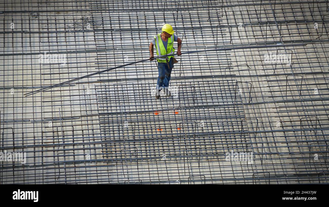 Bauarbeiter, die Stahlarmierungsstäbe auf dem Gelände eines neuen Gebäudes montieren. Mailand, Italien - Oktober 2021 Stockfoto