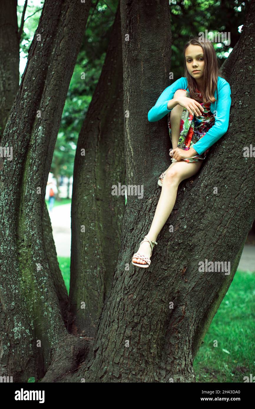 Teenager-Mädchen, das in einem Baum sitzt. Stockfoto