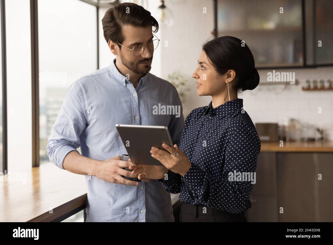 Glückliche junge, gemischte Mitarbeiter mit digitalem Tablet. Stockfoto