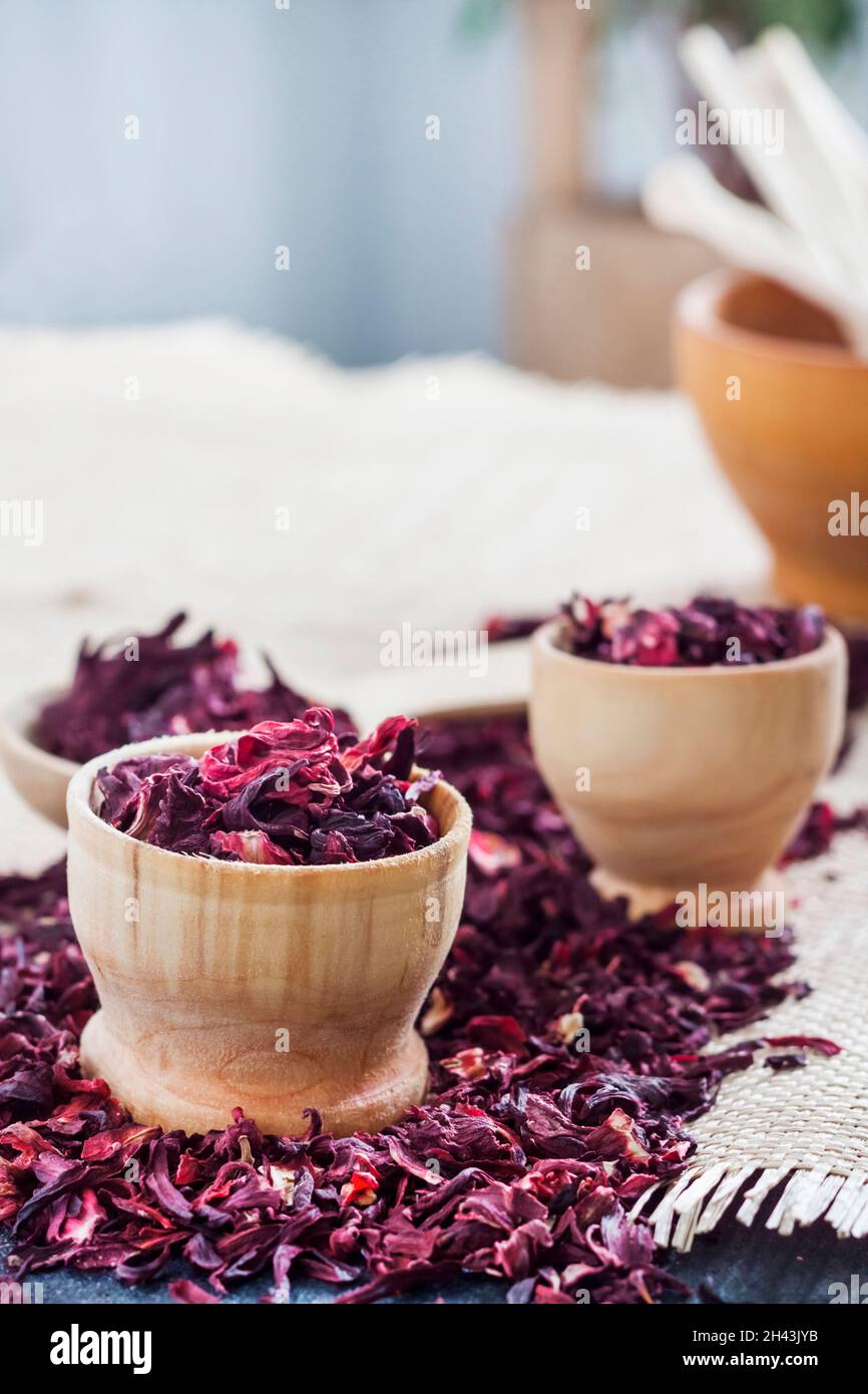 Hibiskustee in Holzlöffel und kleinen Tassen auf einem Tisch mit Strohmatte trocknen Stockfoto