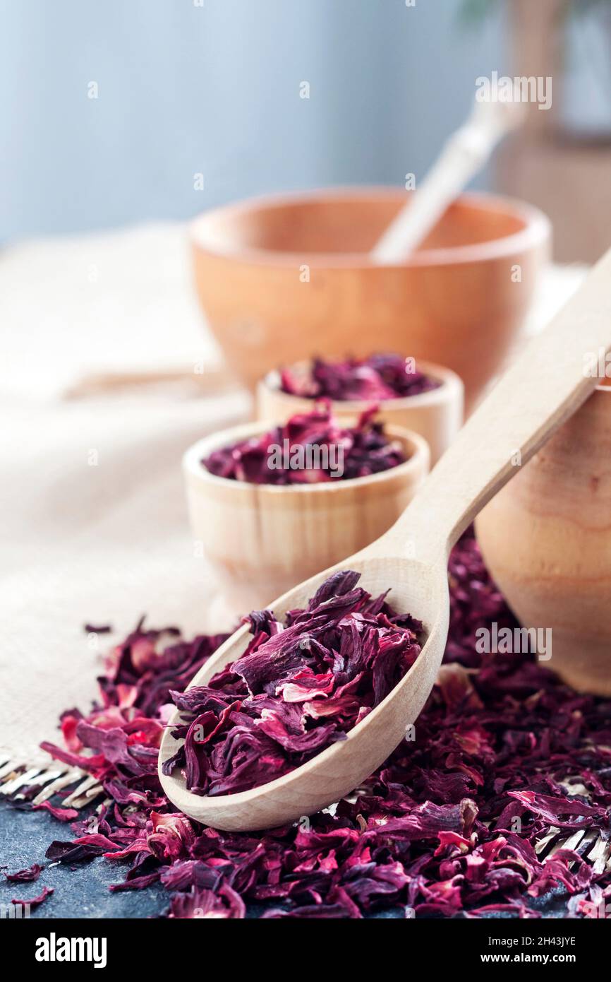 Hibiskustee in Holzlöffel und kleinen Tassen auf einem Tisch mit Strohmatte trocknen Stockfoto