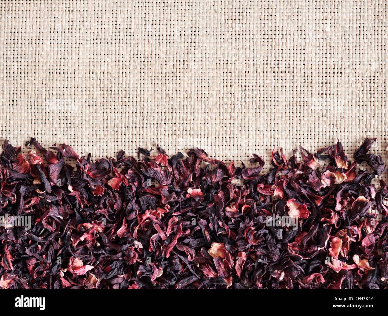 Strohmatte Hintergrund mit trockenem Hibiskustee, Nahaufnahme. Flach liegend, Draufsicht. Stockfoto
