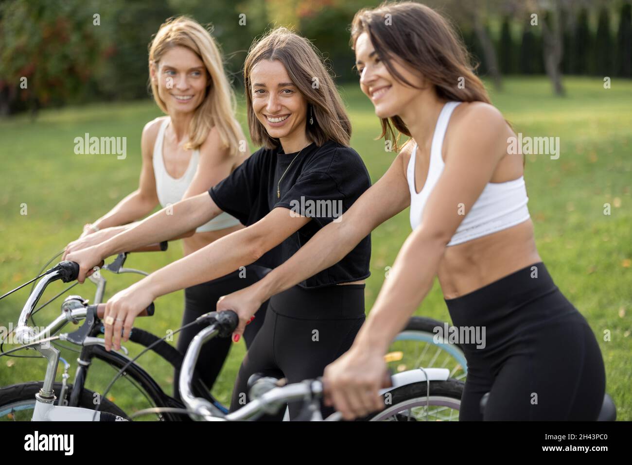 Europäische Freundinnen mit Fahrrädern auf der Wiese Stockfoto
