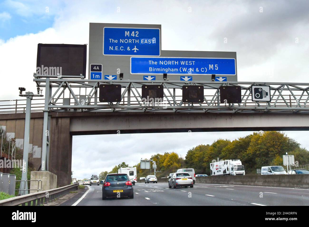 Midlands, England - 2021. Oktober: Auto wird unter einem Straßenschild passieren, das den Fahrern die richtige Spur zeigt, um die Autobahn M5 zu verlassen und auf die M42 zu gelangen Stockfoto