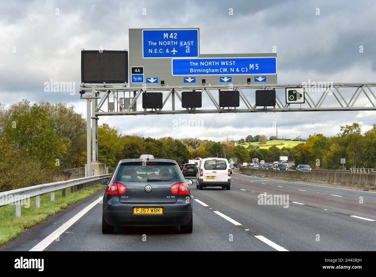 Midlands, England - 2021. Oktober: Auto wird unter einem Straßenschild passieren, das den Fahrern die richtige Spur zeigt, um die Autobahn M5 zu verlassen und auf die M42 zu gelangen Stockfoto