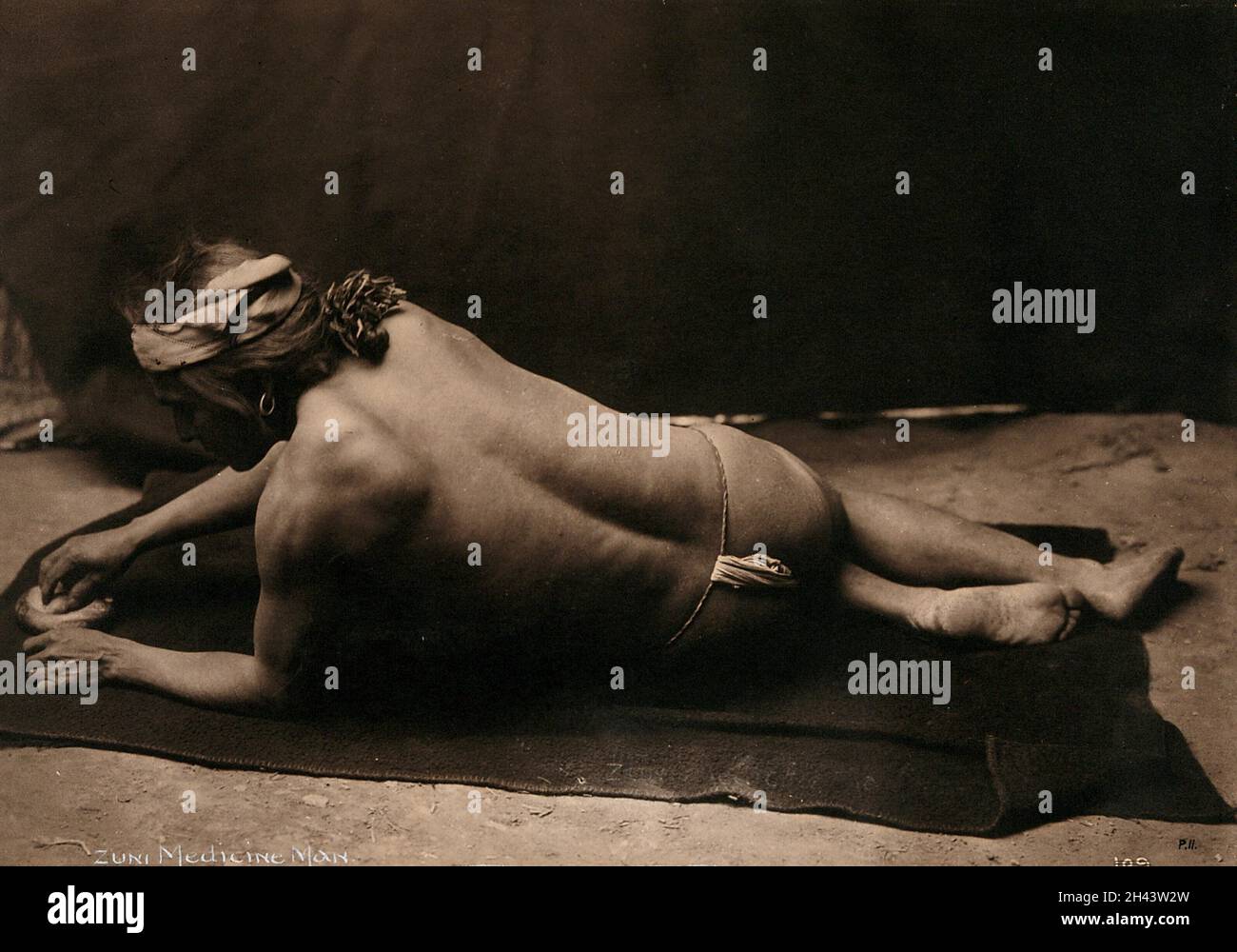 Zuni-Medizinmann, New Mexico: Auf einer Decke liegend, nur mit einem Lendenschurz, zeigt seinen Rücken und sein Gesicht im Profil. Foto (von Edward S. Curtis ?), ca. 1900. Stockfoto