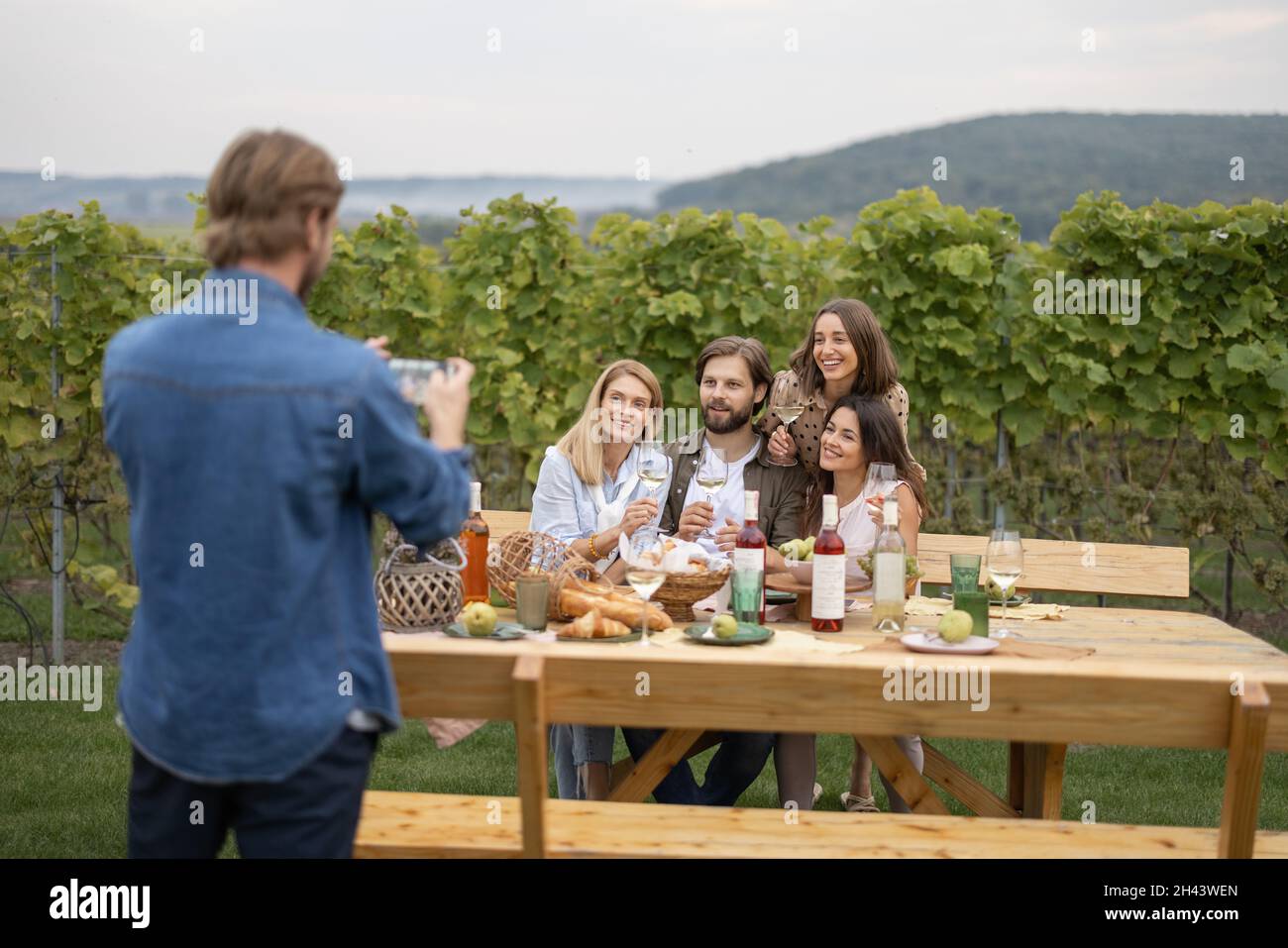 Mann, der auf dem Smartphone Fotos von Freunden beim Picknick gemacht hat Stockfoto