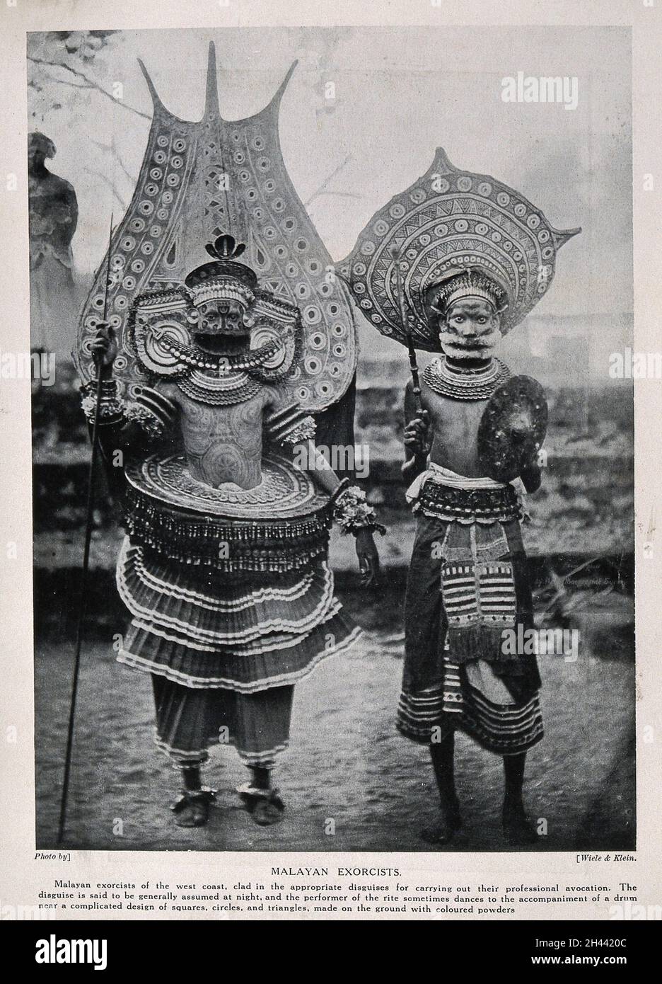 Zwei malaiische Exorzisten in aufwändigem rituellen Kostüm. Halbton nach einem Foto von Wiele & Klein. Stockfoto