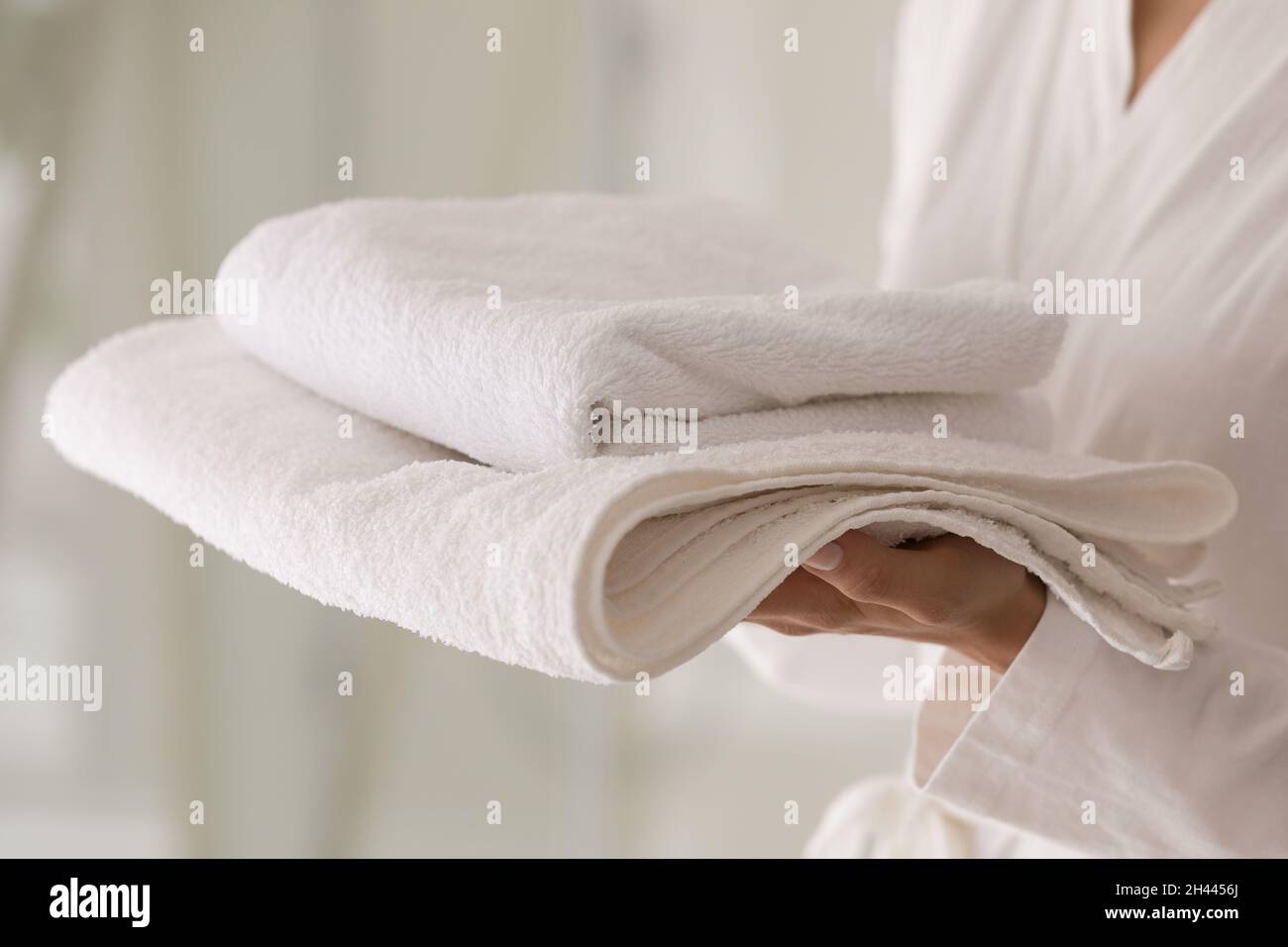 Weibchen hält Stapel frischer weißer Handtücher, Nahaufnahme Stockfoto