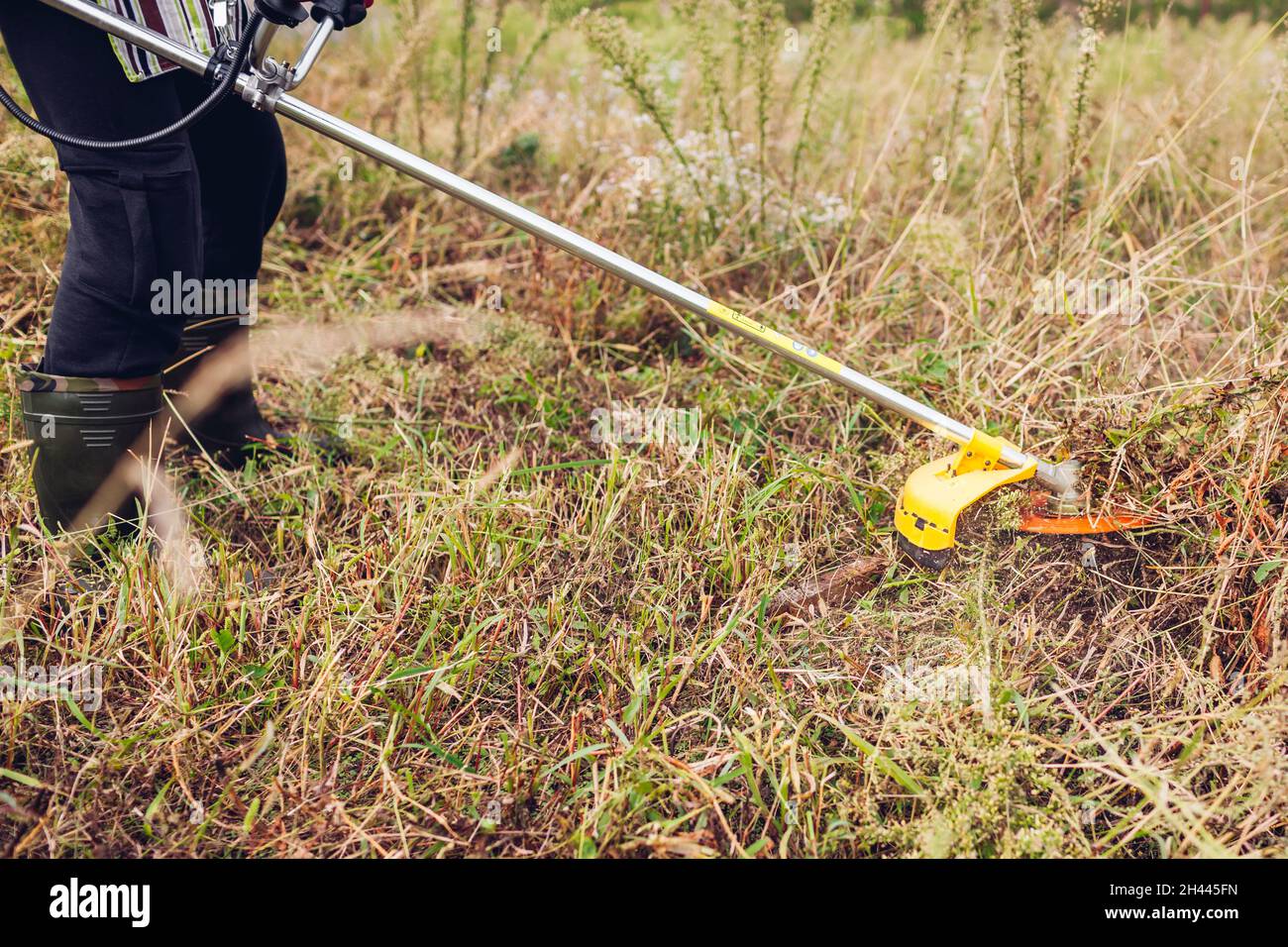 Gärtner mäht Unkraut mit einem Bürstenschneider. Arbeiter trimmen trockenes  Gras mit manuellem Benzin-Trimmer mit Metallklinge Scheibe Stockfotografie  - Alamy