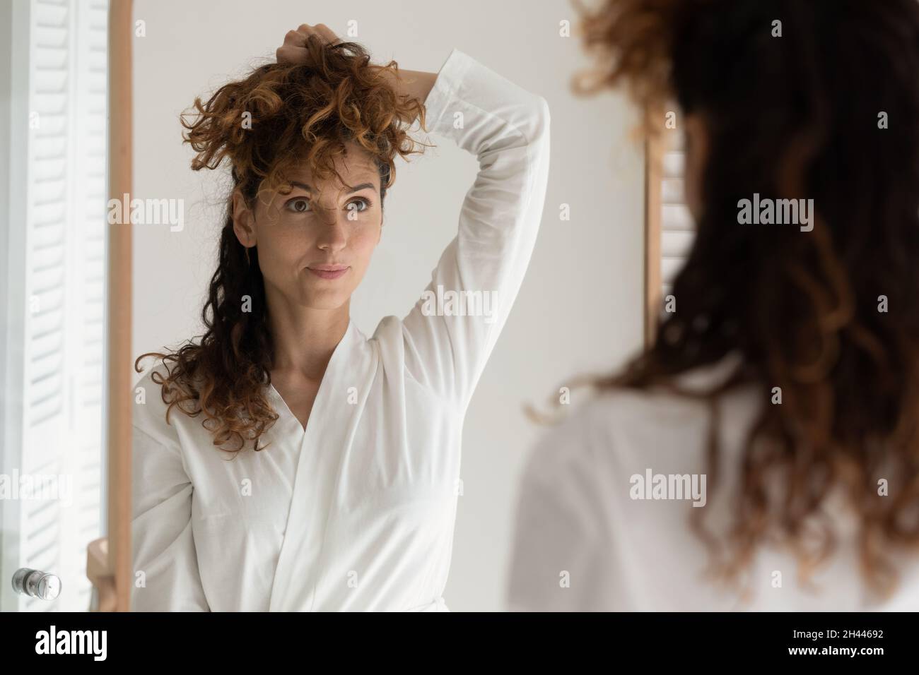 Schöne junge Frau im Bademantel vor dem Spiegel posieren Stockfoto