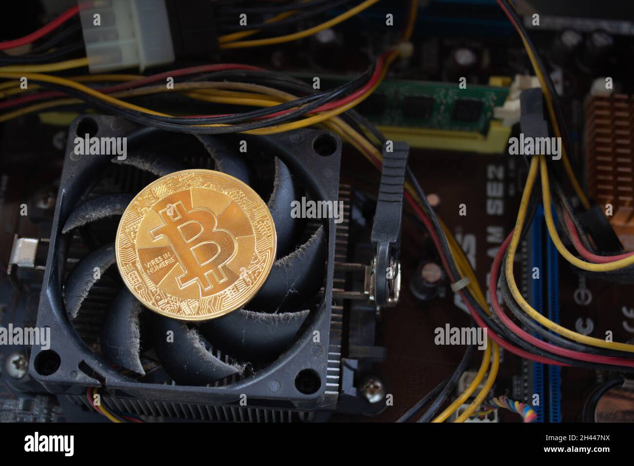 Ein Bitcoin auf einem verschmutzten und alten CPU-Lüfter des Computers. Stockfoto