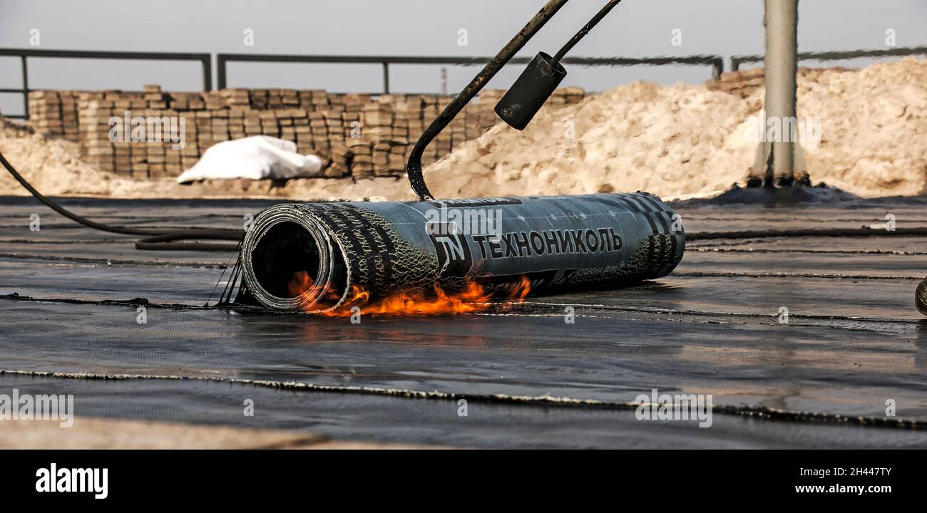 Dnepropetrovsk, Ukraine - 10.28.2021: Der Prozess der Installation von Dachmaterial mit einem Lötbrenner. Der bituminöse Filz schmilzt während der Installation Stockfoto